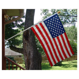 An American flag mounted on a pole, displayed in front of a house entrance.